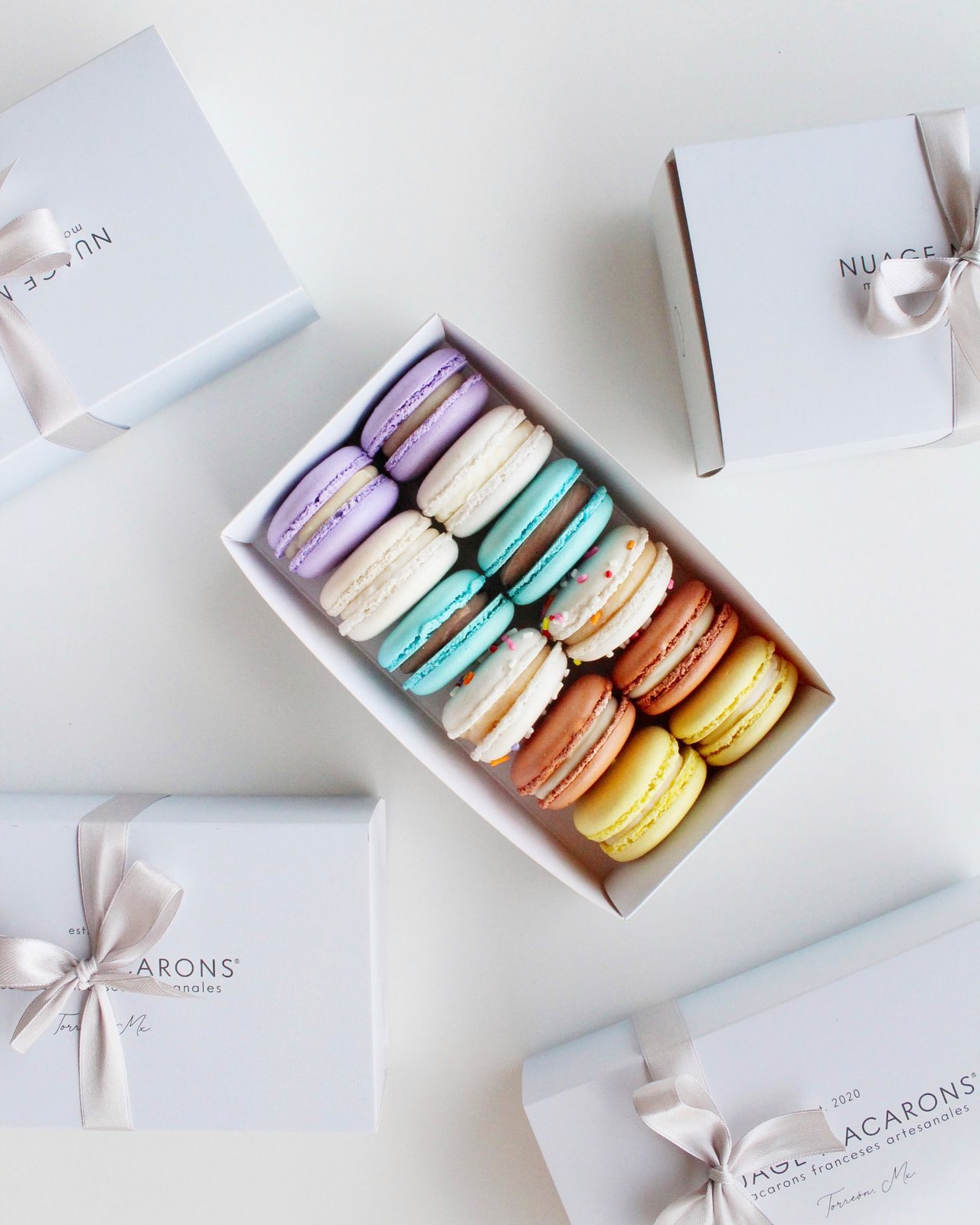 Cajas blancas Nuage con listón y caja abierta de macarons de colores